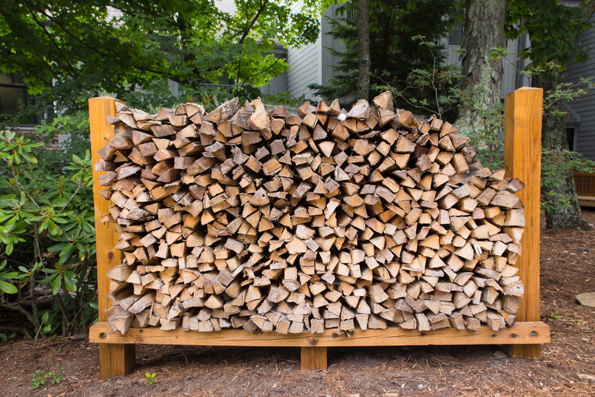 A large pile of chopped firewood on a rack. The wood is neatly arranged.